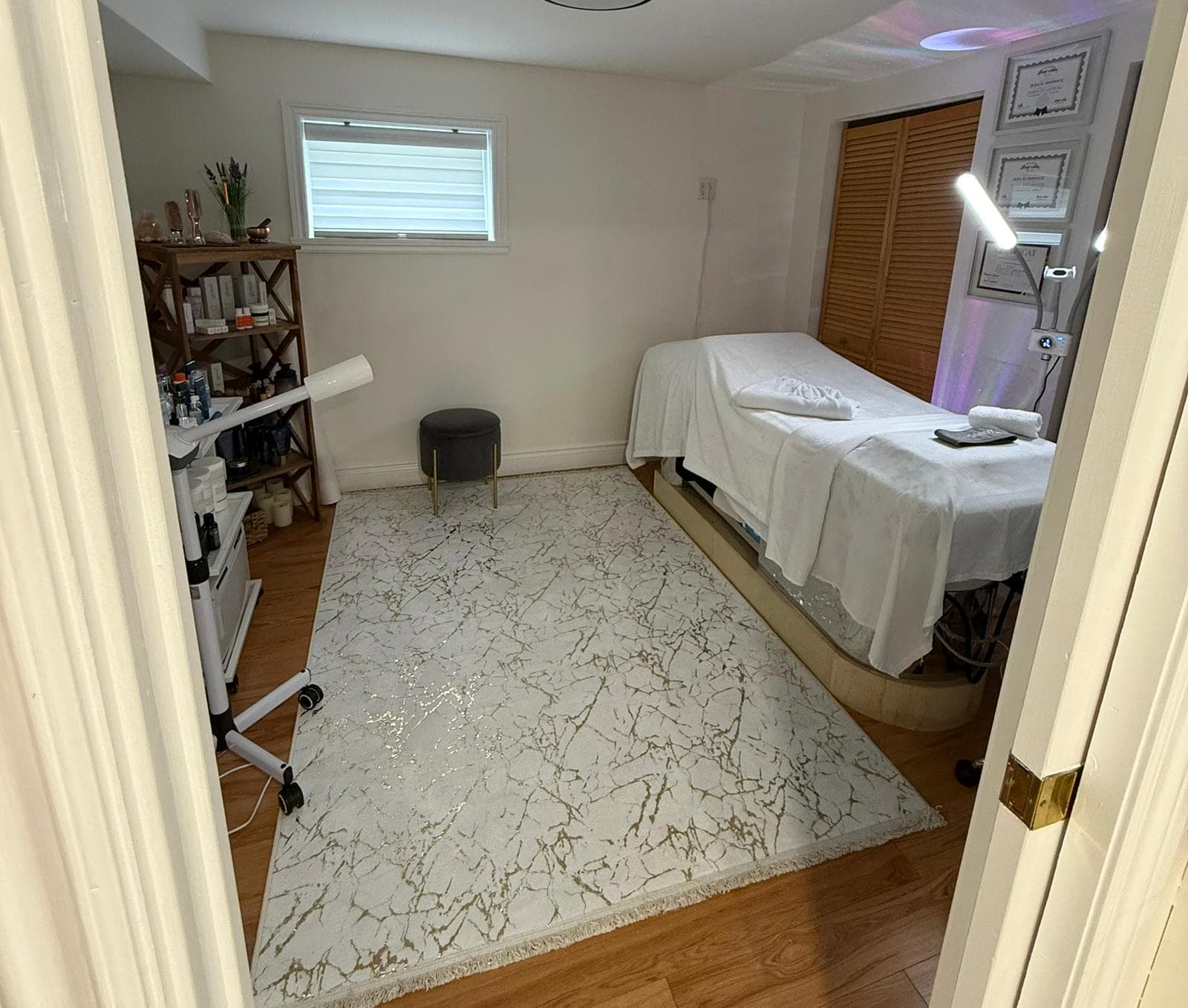Salle de soins professionnelle chez Soin Beauté Rosa : table de traitement, certificats, vaporisateur facial et étagères de produits.